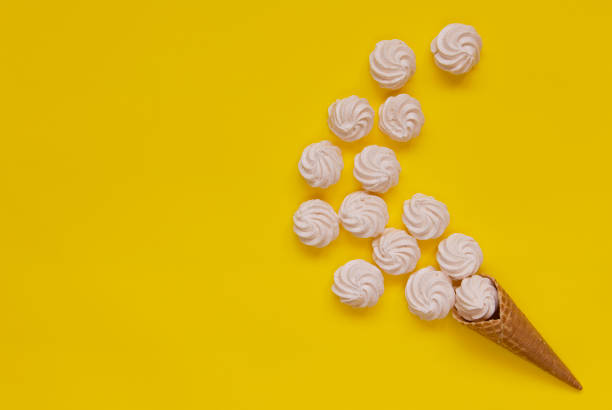 istock Waffle cone and white twisted meringues on yellow background 1166389981
