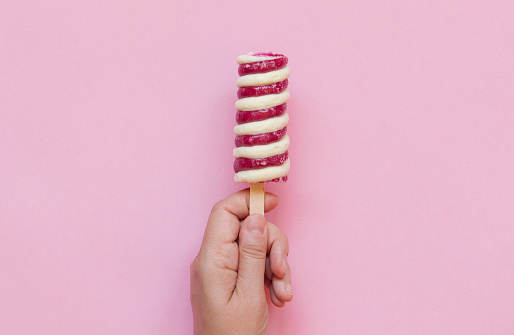 Hand holding Twister ice cream lollipop isolate on pink background