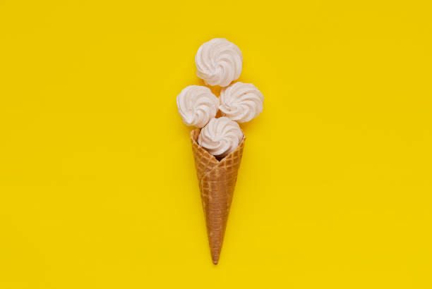 istock Waffle cone and white twisted meringues on yellow background 1166391261