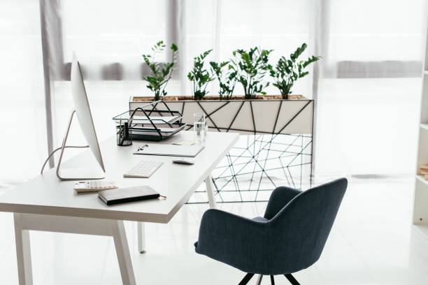 istock white table with computer, document tray, glass and notebook near office chair and flowerpot with plant 1166392786