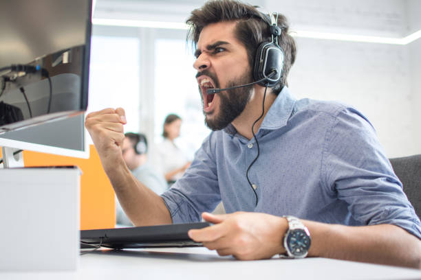 istock Excited handsome male customer support operator with headset celebrating success while working in call centre 1166392860