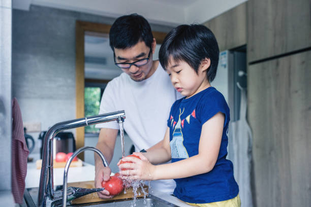 istock Father and son washing Fresh fruit in kitchen sink 1166392896