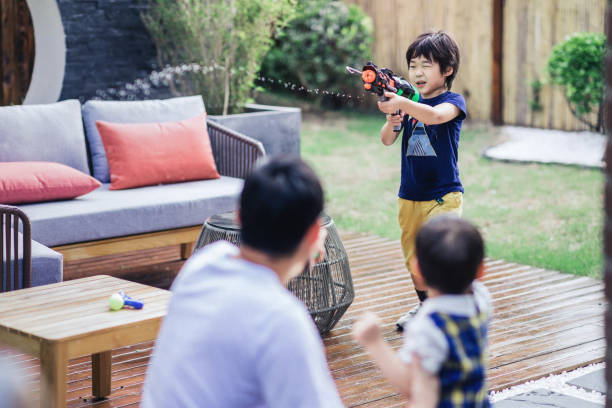 Shot of a father and son playing with squirt guns at home.