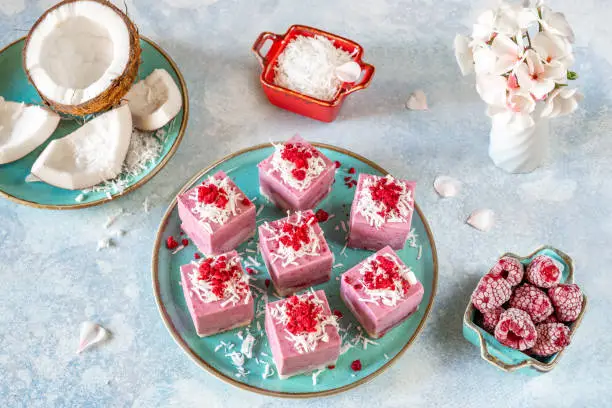 Delicious raw vegan mini-cakes volcanoes made from fermented cashew mousse, with raspberry jam lava, decorated with coconut flakes and slices of sublimated raspberries.Gluten-free, no eggs. Healthy eating concept.