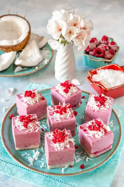 Raw vegan mini-cakes volcanoes made from fermented cashew butter, with raspberry jam lava, decorated with shredded coconut and slices of sublimated raspberries. Gluten-free, no eggs. Healthy eating concept.