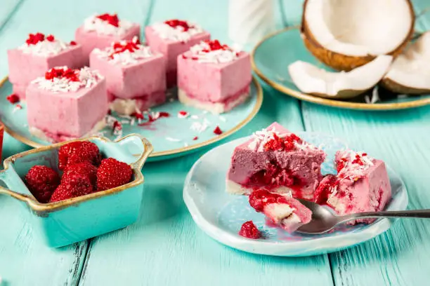 Delicious raw vegan volcano mini-cakes made from fermented cashew mousse, with raspberry jam lava, decorated with shredded coconut and slices of sublimated raspberries. Gluten-free, no eggs. Healthy eating concept.