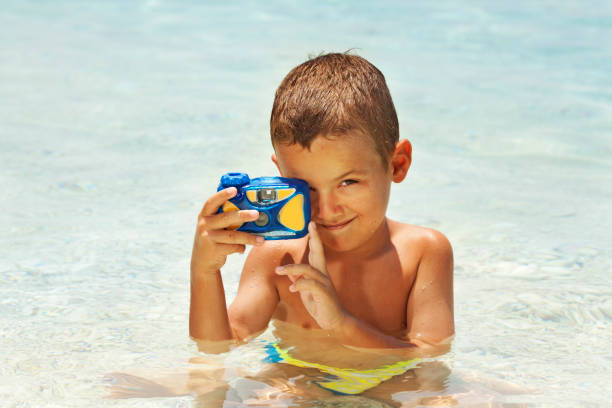 Little boy photographing at the beach Boy holding camera and taking photo at the beach underwater camera stock pictures, royalty-free photos & images