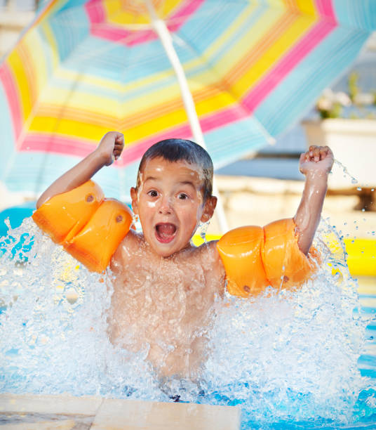 ragazzo giocoso che spruzza in piscina - child swimming pool swimming little boys foto e immagini stock