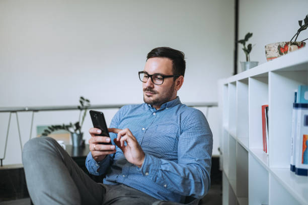 istock Man sitting on chair and using his phone. 1166399253