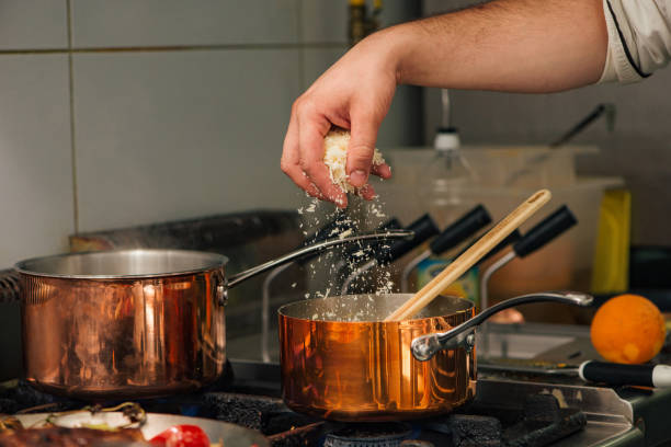 Chef cooking, adding parmesan cheese. Preparing delicious food, close-up.