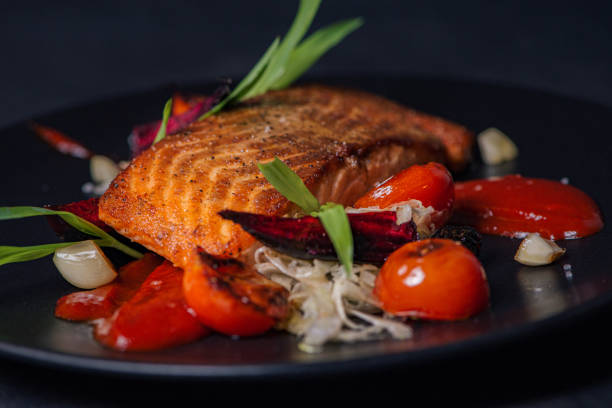 bistecca di salmone servita con verdure su un piatto nero. - 2546 foto e immagini stock