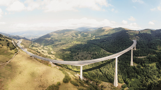 A large, high multiple lane highway viaduct in a beautiful green valley