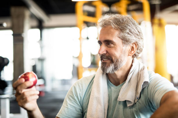 istock Mature man eating an apple in a gym. 1166400196