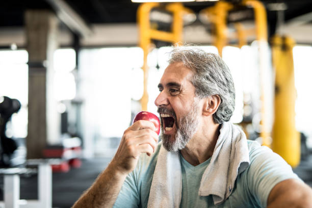 istock Mature man eating an apple in a gym. 1166400352