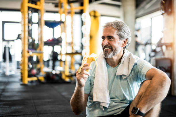 istock Mature man eating a banana in a gym. 1166401104