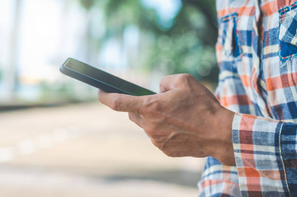istock close up handsome man using hand typing mobile phones and touch screen working search with app devices outdoor in city with sunrise and building background. 5G technology connecting the world. 1166404711