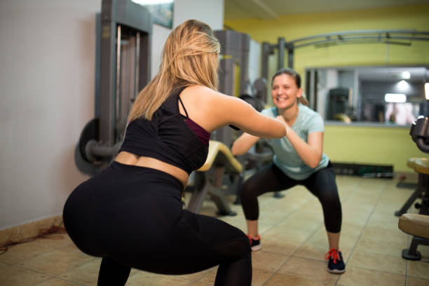 istock Female fitness instructor squatting with her client 1166404863