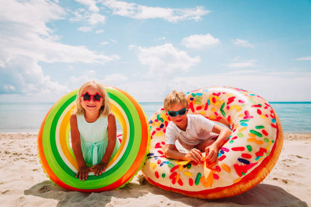 istock happy cute boy and girl play with floaties on beach 1166405387