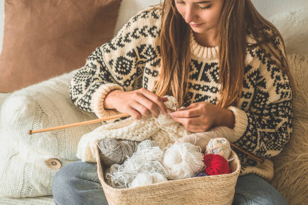 красивая девушка вяжет теплый свитер на кровати. вязание как хобби. аксессуары для вязания - crochet стоковые фото и изображения
