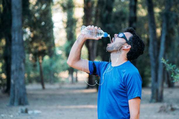 istock white man drinking water and listening to music in a park while exercising. 1166417206