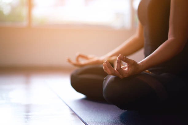 mujeres en meditación mientras practican yoga en una sala de entrenamiento. feliz, tranquilo y relajante. - meditating fotografías e imágenes de stock