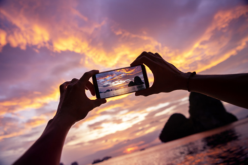 Closeup photo of hands taking a photo from mobile phone. Krabi province, Railay beach on background