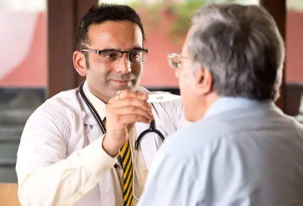 Photo of Doctor checking senior man's temperature