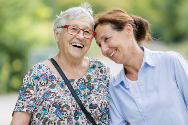 szczęśliwa starsza kobieta i opiekunka chodząca na świeżym powietrzu - community outreach aging process human age retirement zdjęcia i obrazy z banku zdjęć
