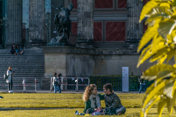 leidenschaftliches paar sitzt im gras und genießt das sonnenlicht im lustgarten, einem park der museumsinsel, vor dem alten museum, einem weltkulturerbe - berlin cathedral berlin germany museum island sunlight stock-fotos und bilder