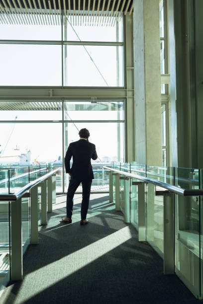 istock Businessman talking on mobile phone in corridor at modern office building 1166423320