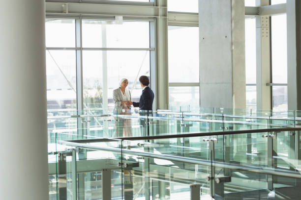 istock Business people shaking hands together in corridor at modern office 1166424140