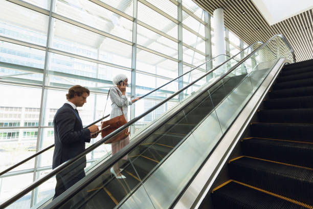 istock Business people talking on mobile phone and using digital tablet on escalator in a modern office 1166424215