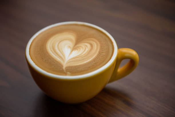 istock Heart shape latte art in yellow cup on wooden table 1166425921
