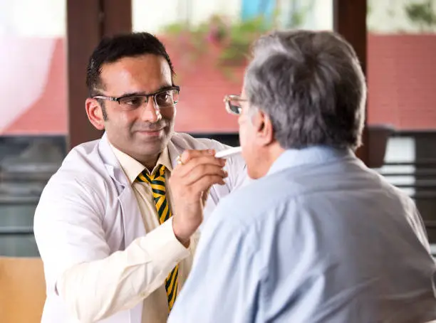 Photo of Doctor checking senior man's temperature