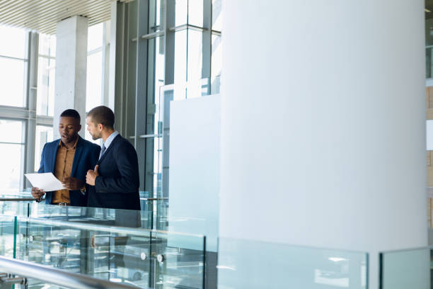istock Two businessmen stand talking in modern business building 1166429145