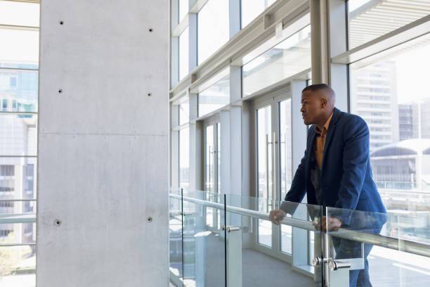 istock Businessman looking away standing in modern office lobby 1166429207