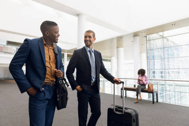 istock Two businessmen talking while travelling with luggage 1166429764