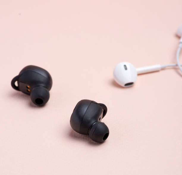 istock black wireless and white earphones with wire on a beige background 1166432260