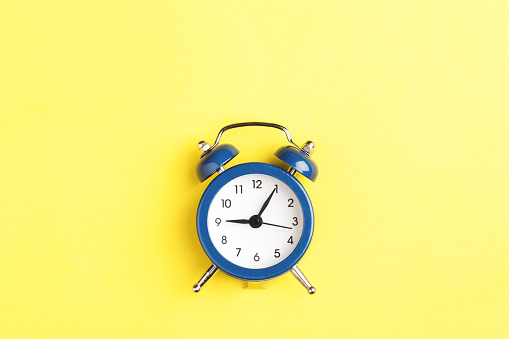 Alarm clock on yellow background. Minimal styled photo.