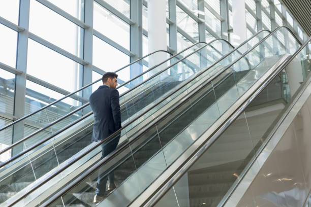 istock Businessman going up an escalator in modern building 1166434761