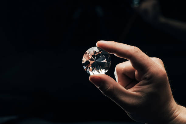 istock partial view of man holding big clear shiny diamond on black background 1166434896