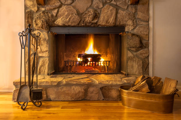 stone fireplace with logs burning in a residential home. - fire place imagens e fotografias de stock