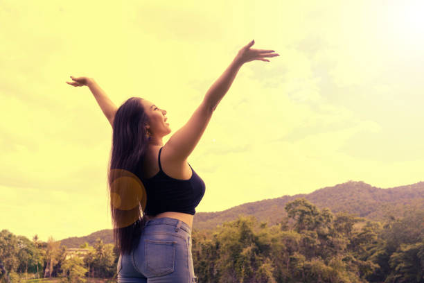 Happy Woman hands up to sky feel freedom confident and independent over sunset sky