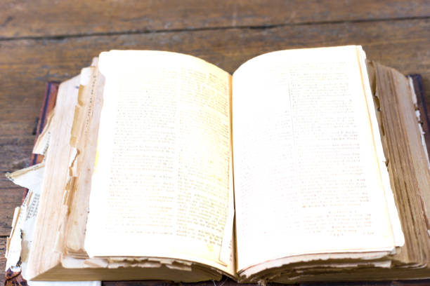 istock Antique Worn and Torn Open Book, Brown Wood Background 1166437730