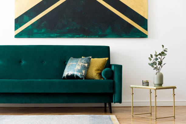 istock Luxury and minimalistic composition of home interior design with stylish velvet sofa, pillows, gold coffee table, flowers in vase and elegant accessories. Modern home decor. Template. White walls. 1166437794