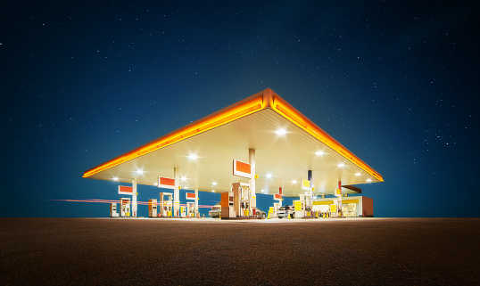Unbranded Gas station with retail convenience store at night time .