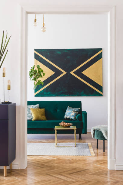 istock Luxury composition of home interior design with modern velvet sofa, pouf, shelf, pillows, coffee table, plants, elegant accessories and geometric paintings on the wall. Stylish home decor. Template. 1166437937