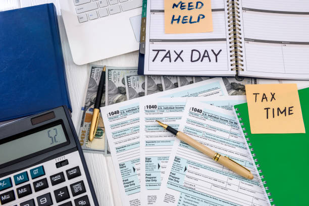 istock Top view at 1040 form, dollar, laptop and calculator 1166438402