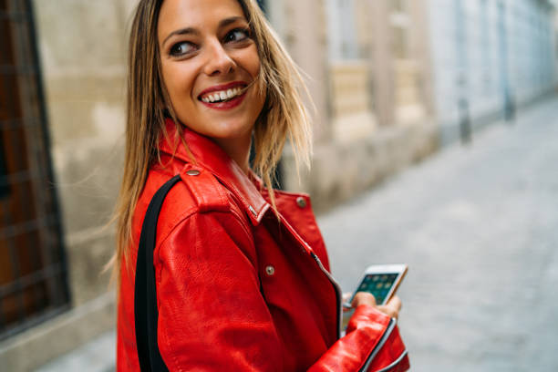 istock A smiling lady dressed in a red jacket, chatting with her smartphone 1166439335
