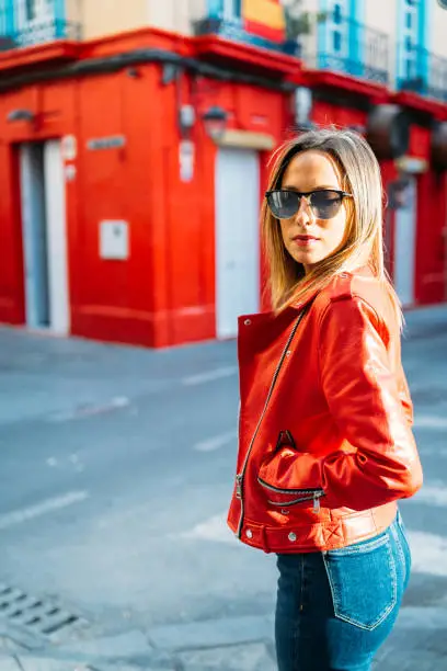 Photo of Attractive woman dressed in red jacket and sunglasses posing in the street